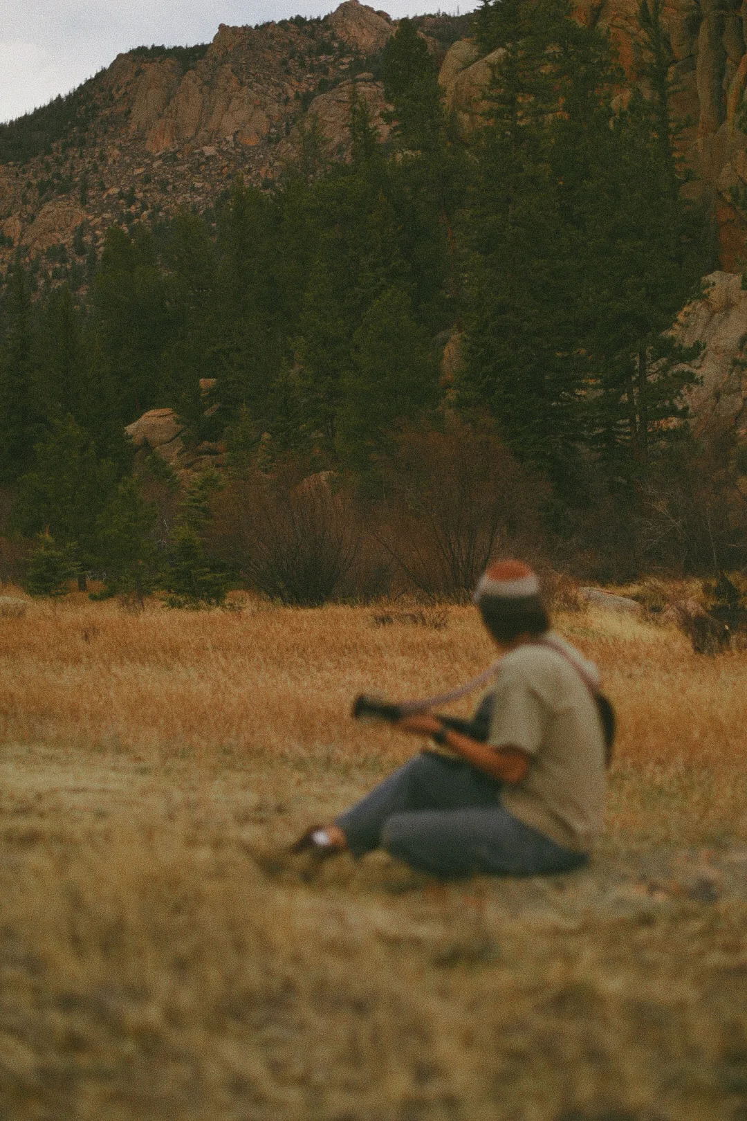 Quincy seated with his guitar in a Colorado field